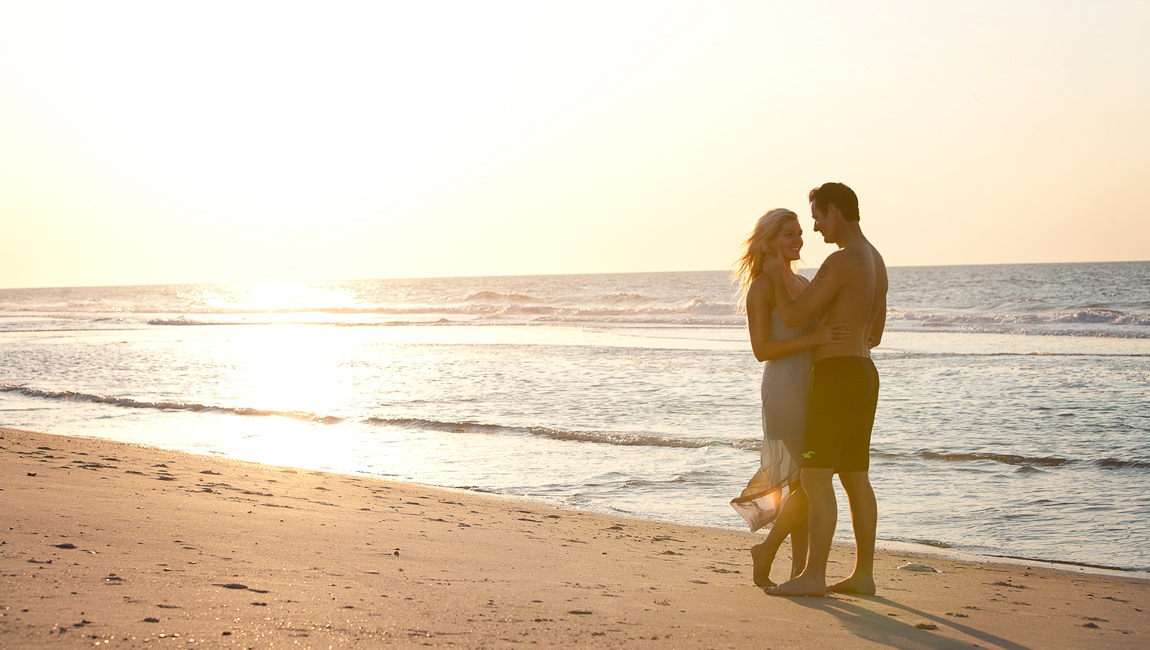 A couple embracing on a beach at sunset.