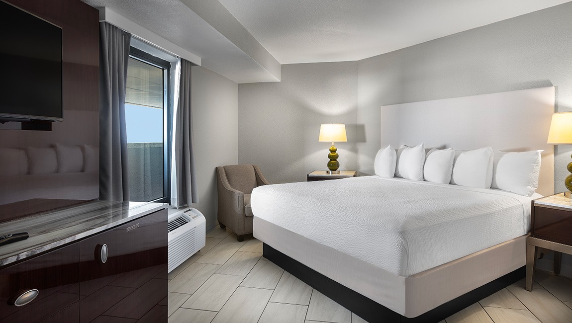 A hotel room with a king-sized bed, TV, and window