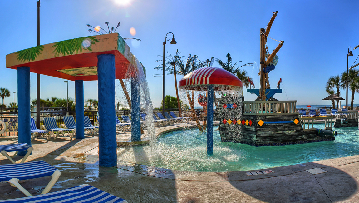 A colorful outdoor pool with water features and lounge chairs.