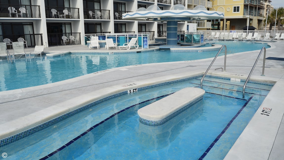 A swimming pool with a white lounge chair and blue water.